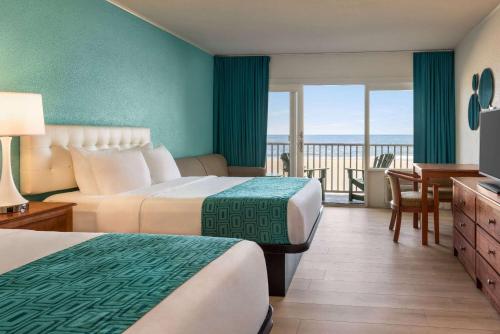 オーシャンシティにあるHoward Johnson by Wyndham Ocean City Oceanfrontのベッド2台とバルコニーが備わるホテルルームです。