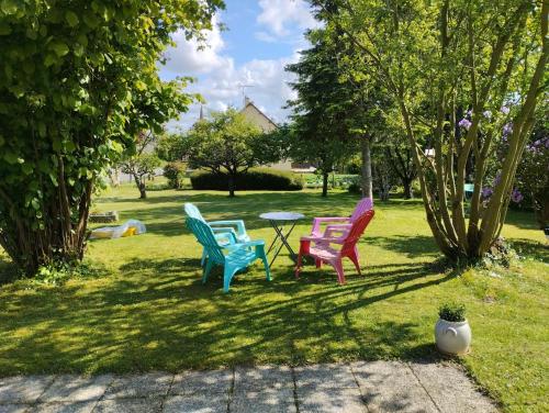 four colorful chairs and a table in a park at chambres d'hôtes du clos du roi in Pontorson