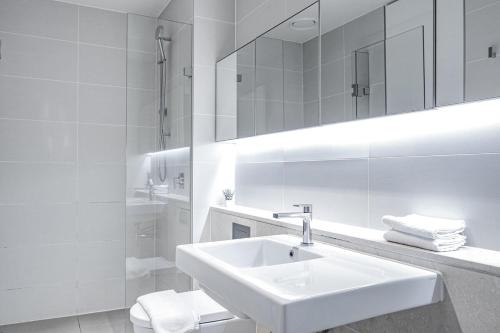 uma casa de banho branca com um lavatório e um espelho em Nice View 2br Apt At William St Pool Gym Balcony em Melbourne
