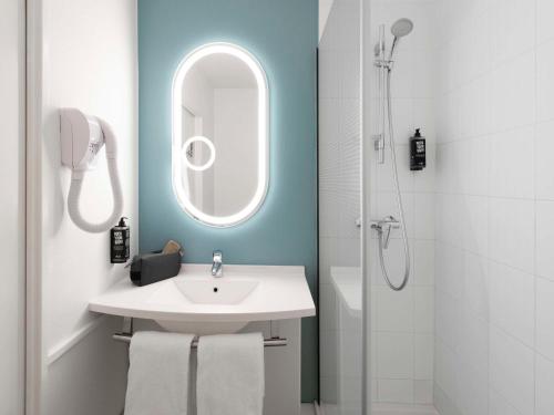 La salle de bains est pourvue d'un lavabo, d'un miroir et d'une douche. dans l'établissement ibis Nancy-Brabois, à Vandœuvre-lès-Nancy