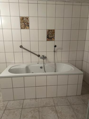uma banheira numa casa de banho em azulejos brancos em Appartment for Rent 02 em Burgwedel