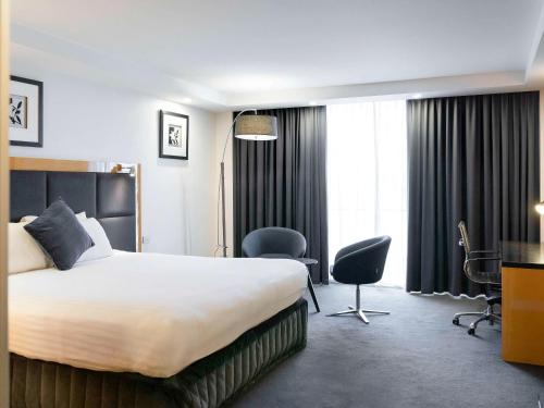 アデレードにあるアデレード ロックフォードのベッド、デスク、椅子が備わるホテルルームです。