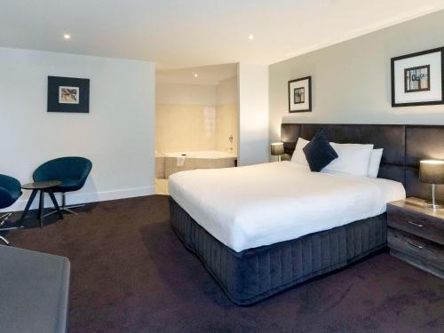 a hotel room with a large bed and a desk at Adelaide Rockford in Adelaide