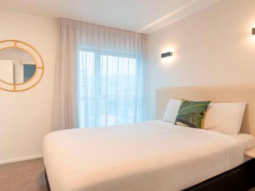 a bedroom with a large white bed and a window at Mercure Wellington Central City Hotel and Apartments in Wellington