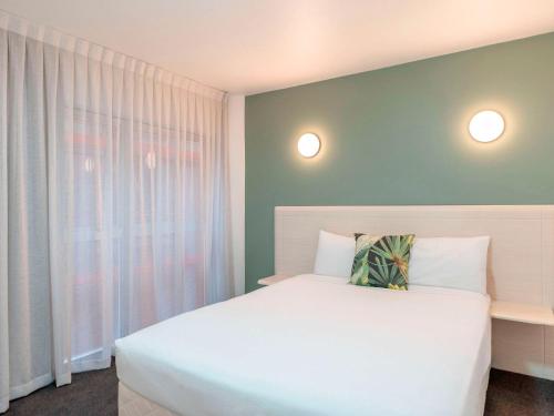a bedroom with a white bed and a window at Mercure Wellington Central City Hotel and Apartments in Wellington