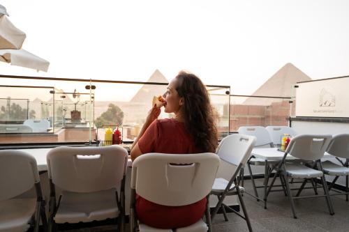 a woman sitting at a table eating a hot dog at Sun and Sand Guest House in Giza