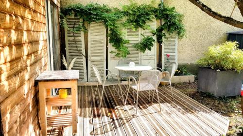 Un patio con una mesa y sillas en un porche. en A la ville comme à la campagne, en Sainte-Savine