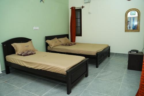 2 Betten in einem Zimmer mit Spiegel in der Unterkunft UNGA VEEDU PAY AND STAY in Tiruvannāmalai