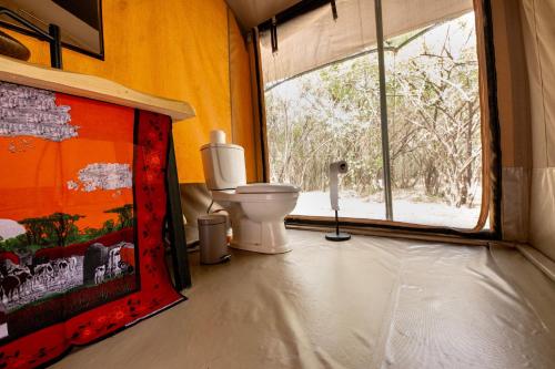 a bathroom with a toilet and a window at Olkinyei Mara Tented Camp in Talek