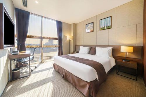 Ramada by Wyndham Incheon في انشيون: غرفة فندقية بسرير كبير ونافذة كبيرة