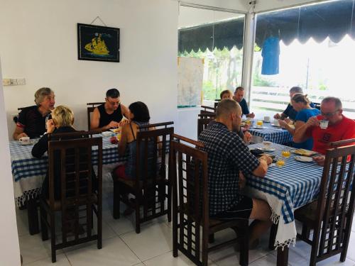 um grupo de pessoas sentadas em mesas em um restaurante em Sunflower Inn em Dambulla
