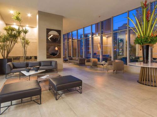 a lobby with leather furniture and large windows at Novotel Medellin El Tesoro in Medellín