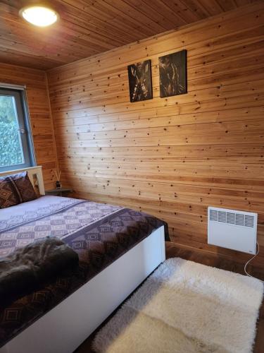 ein Schlafzimmer mit einem Bett in einer Holzwand in der Unterkunft LE GLAWAN in Barvaux