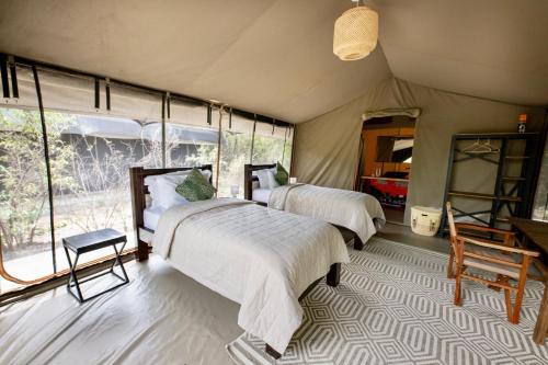 Talek的住宿－Olkinyei Mara Tented Camp，一间帐篷内带两张床的卧室