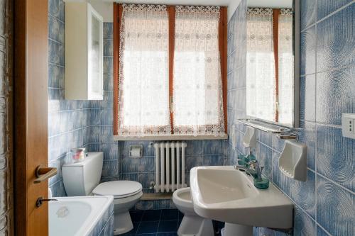 een blauw betegelde badkamer met een toilet en een wastafel bij La Serena di Bordighera Vintage Flat in Bordighera