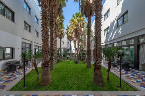 un patio con palmeras en un edificio en Grand Hotel Sofia, en Noto