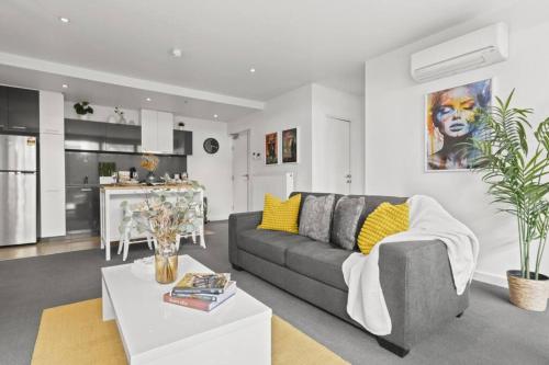 a living room with a gray couch and a kitchen at Ink Echelon Escape in Melbourne