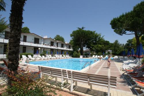 een zwembad met stoelen en een persoon die voor een hotel staat bij VILLAGGIO LIDO - Cavallino in Cavallino-Treporti