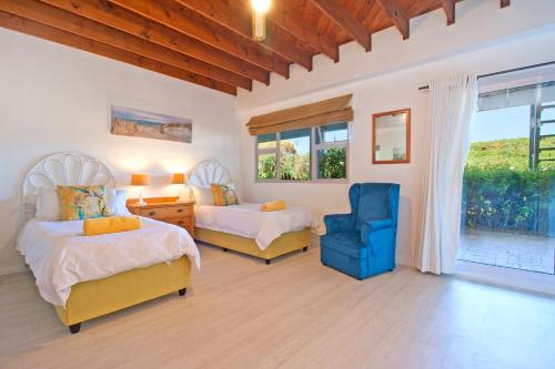 a bedroom with two beds and a blue chair at Atlantic Dream Beachfront Villa in Scarborough