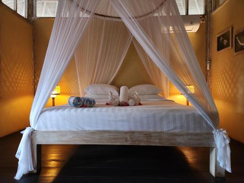 a bedroom with a canopy bed with white sheets and pillows at Bamboo Lodge in Gili Trawangan