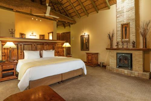 a bedroom with a large bed and a fireplace at Cathedral Peak Hotel in Winterton