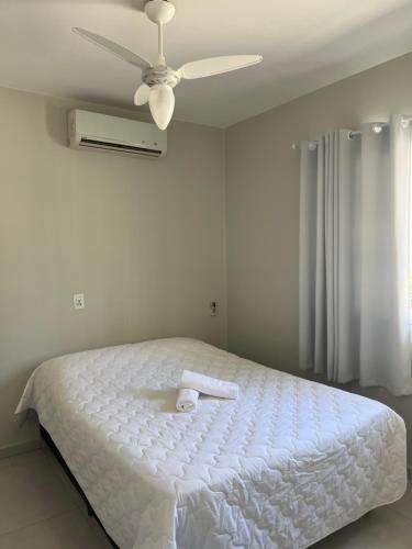 Schlafzimmer mit einem weißen Bett und einem Deckenventilator in der Unterkunft Casa com piscina em Itapema próximo a praia in Itapema
