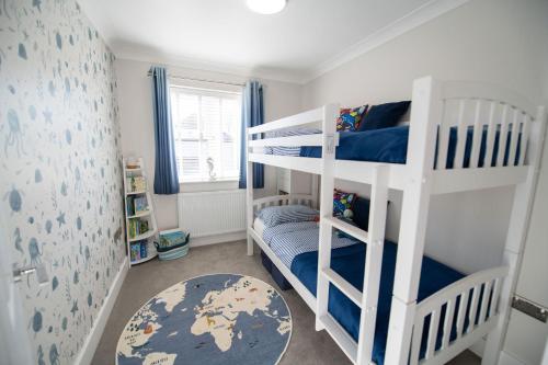 a room with two bunk beds and a rug at La Casita - Inside the Gates of Frinton-On-Sea in Frinton-on-Sea