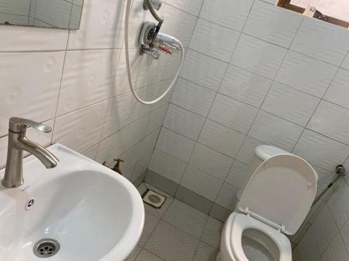 a white bathroom with a sink and a toilet at Twinkle Blue Inn in Namugongo