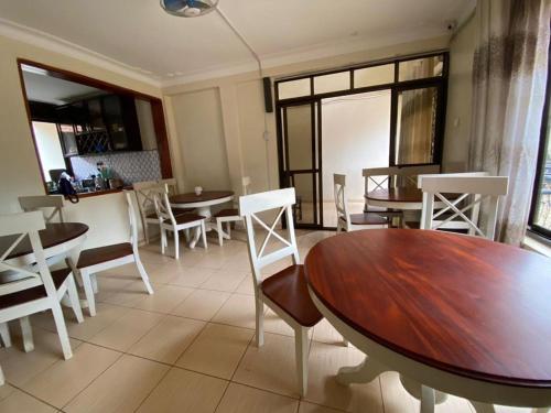 a dining room with tables and white chairs at Twinkle Blue Inn in Namugongo