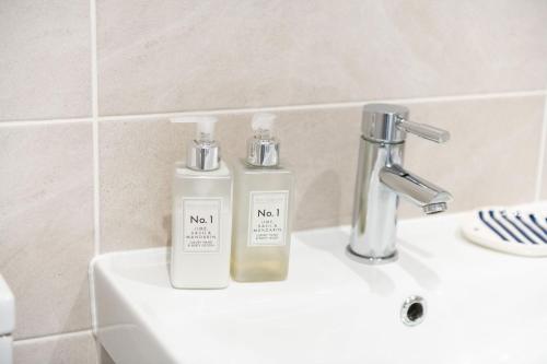 two bottles ofodorizers sitting on a sink in a bathroom at La Casita - Inside the Gates of Frinton-On-Sea in Frinton-on-Sea