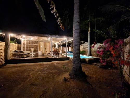 a house with a tree and a swimming pool at night at Bamboo Lodge in Gili Trawangan