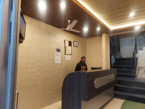 a man standing at a reception desk in a building at Hotel Always Welcome by SAH in Mount Ābu