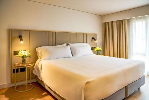 a large white bed in a room with a window at NH Bogota Pavillon Royal in Bogotá