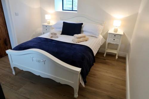 a small bedroom with a white bed and a night stand at Tara’s Hill Cottage in Kilcoo