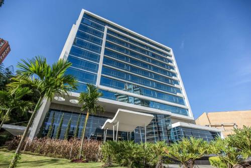 a tall building with palm trees in front of it at NH Collection Medellin Royal in Medellín