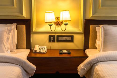 a hotel room with two beds and a phone on a table at Clarks Inn Express, Rishikesh in Rishīkesh