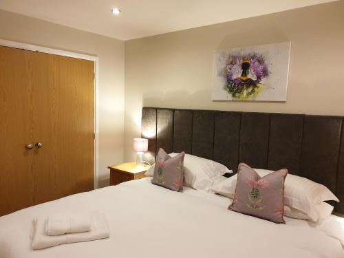 a bedroom with a large white bed with pink pillows at Peaceful relaxing home with leisure in Saint Columb Major