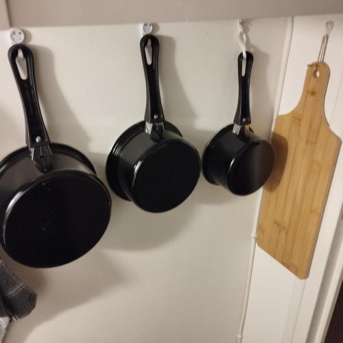 4 casseroles et poêles noirs accrochées à un mur dans l'établissement Home sweet to Paris, à Clichy