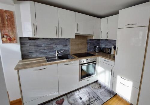 una cocina blanca con armarios blancos y fregadero en Appartement Twin Peak Edelweiss en Gosau