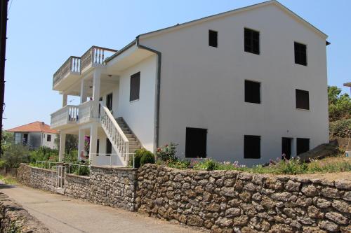 a large white house with a stone wall at Apartment Dragovic in Ulcinj