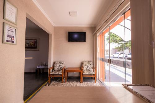 a hallway with a table and two chairs and a window at Pousada Ma-juli in Olímpia