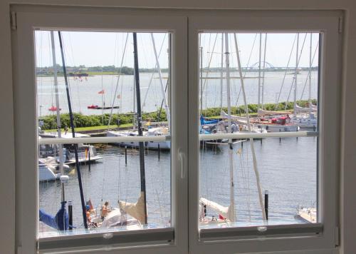 ein Fenster mit Blick auf einen Yachthafen mit Booten in der Unterkunft Meerblick Lemkenhafen in Fehmarn