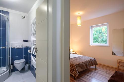 baño con aseo, cama y ventana en Apartment Lovro en Punat