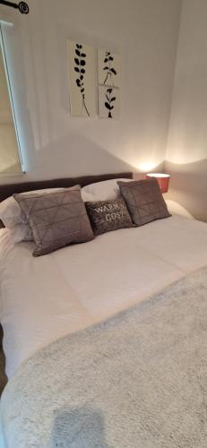 um quarto com uma cama com lençóis brancos e almofadas em MarMic Cottage em Rothbury