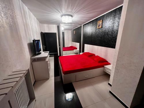 um pequeno quarto com uma cama vermelha em Apartament zona fabricii Ford em Craiova