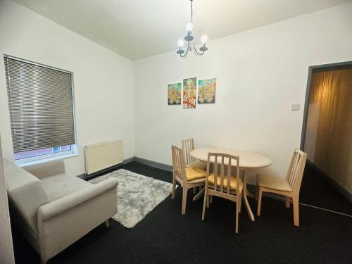 een woonkamer met een tafel en stoelen en een bank bij Samco flat in Ashton-in-Makerfield