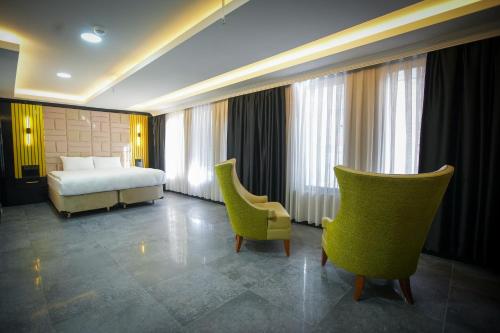 um quarto de hotel com uma cama e duas cadeiras em KY Continental Apartments em Izmir