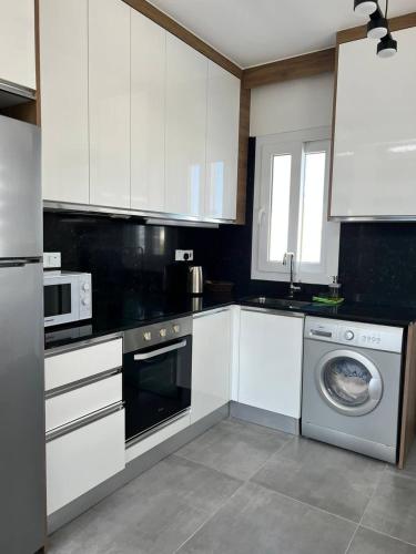 a kitchen with white cabinets and a washing machine at Four seasons sea holiday in Iskele