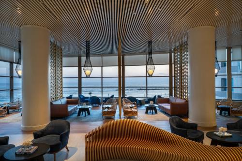 a lobby with chairs and tables and a large window at Leonardo Plaza Haifa in Haifa
