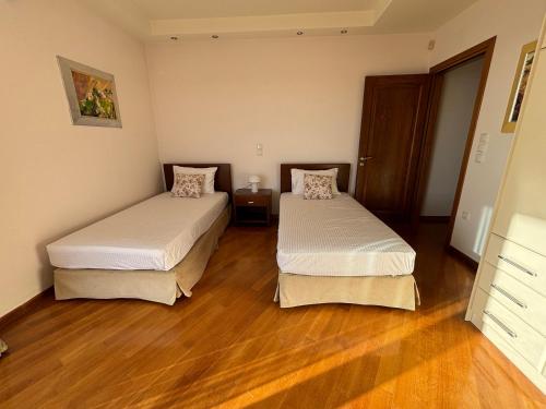 two beds in a room with wooden floors at Liberty - Classic luxury sea view villa with private pool, Panoramic views to Kommeno & Corfu old Town in Kommeno